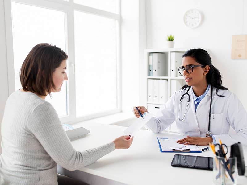 a female doctor goes over a piece of paper with a female patient