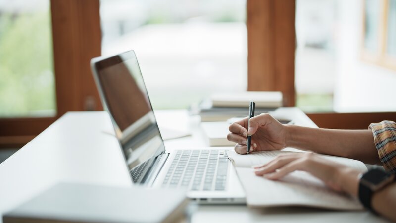 person in front of laptop taking notes