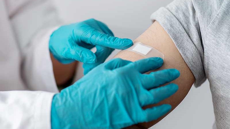 nurse in gloves putting band aid on patient's arm