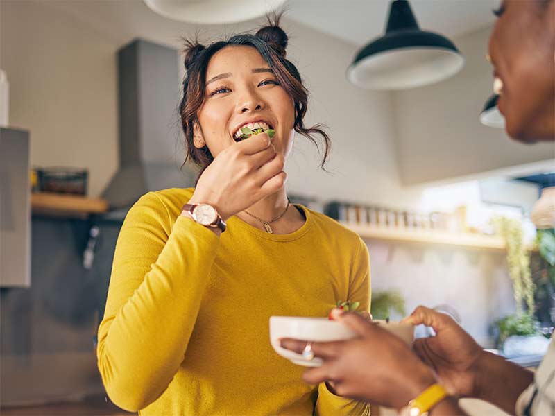 a woman smiles while eating a strawberry