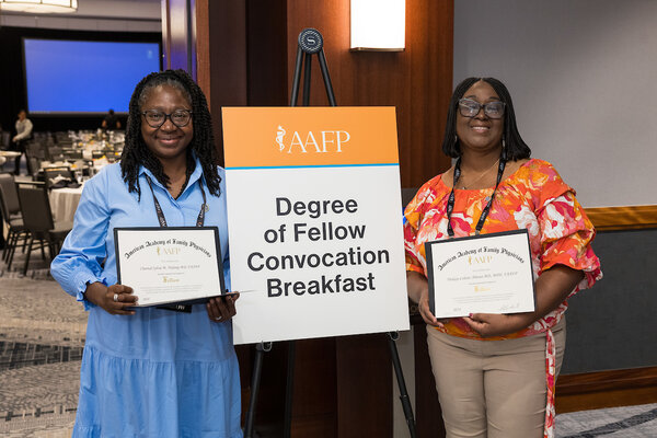 Two women physicians holding certificates attending the convocation breakfast