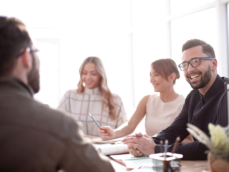 Four adults around a table smiling with textbooks on the table