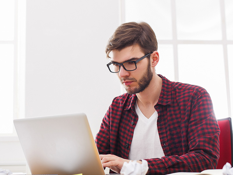 Man with glasses working on a laptop at a desk