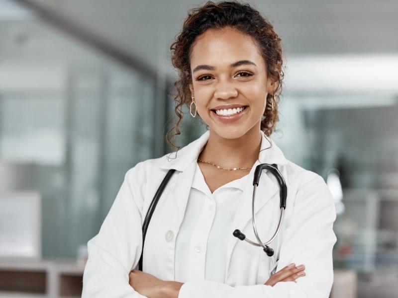 Close up of young black female doctor with stethoscope around her neck and arms crossed smiling