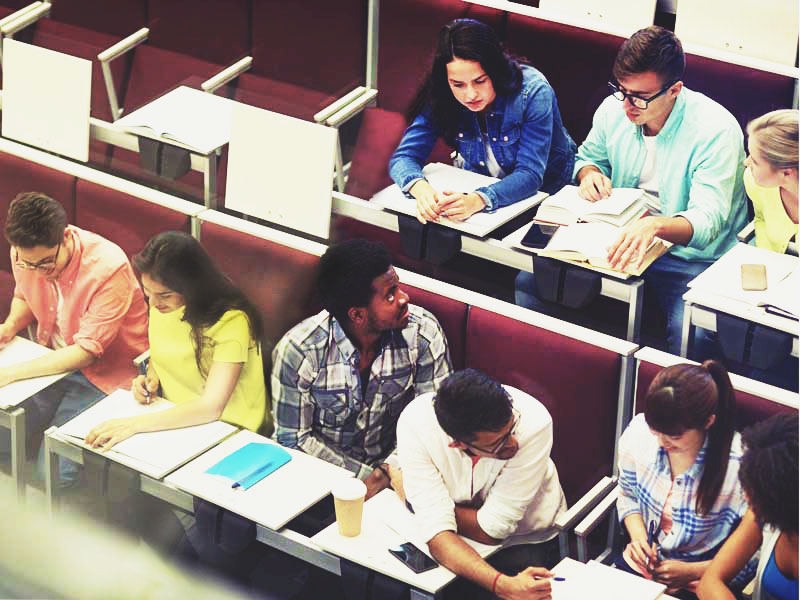 Eight women and men sitting in two rows in a classroom setting talking with one another