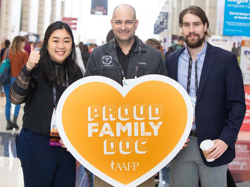 Image of three people hold a heart that reads proud family doc. 