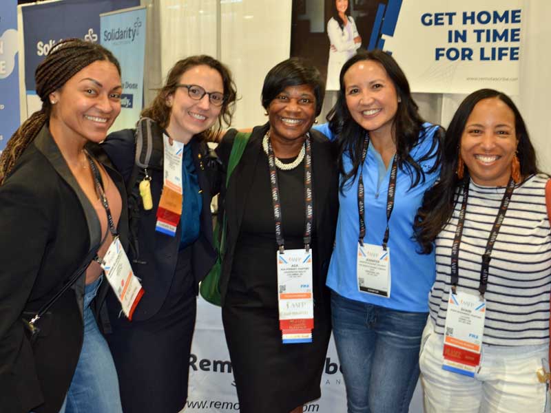 Jennifer Bacani McKenney, M.D., FAAFP, second from right, poses in front of her booth